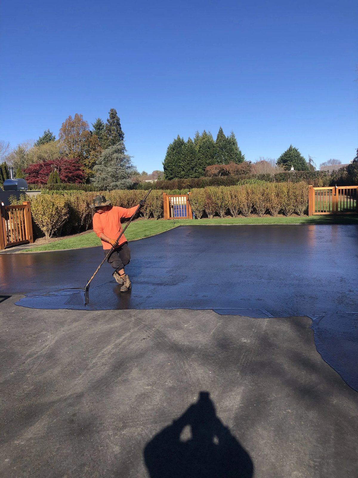 Worker applying sealcoat to an asphalt driveway with a squeegee